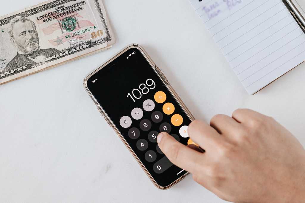 iPhone next to stack of bills and a notepad